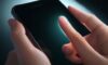 Nahaufnahme eines Fingers, der eine leuchtende Smartphone-Oberfläche berührt, wobei die Interaktion zwischen Haut und Glas durch eine Lichtwelle hervorgehoben wird.